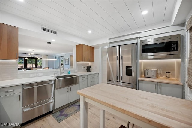 kitchen featuring wooden ceiling, sink, light hardwood / wood-style flooring, decorative backsplash, and stainless steel appliances