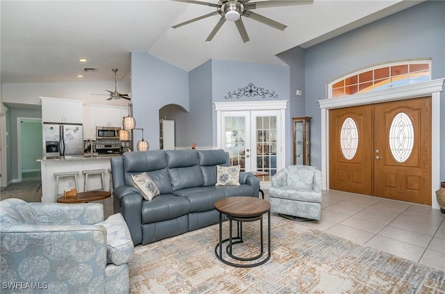 tiled living room featuring ceiling fan, french doors, and vaulted ceiling