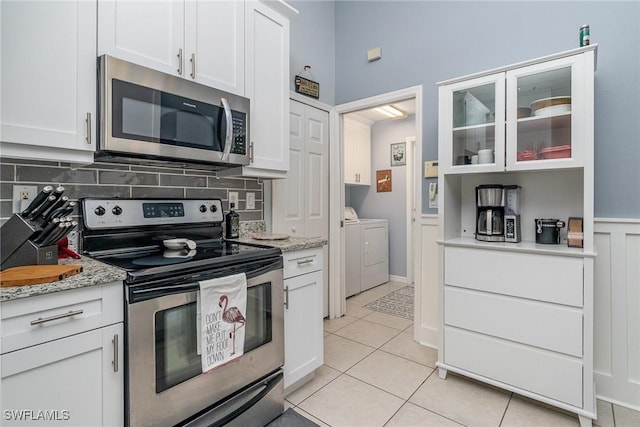 kitchen featuring washing machine and dryer, white cabinets, and stainless steel appliances