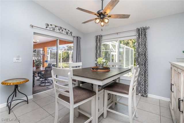 dining area with ceiling fan, light tile patterned flooring, and vaulted ceiling