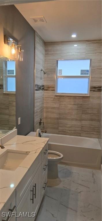 full bathroom with toilet, vanity, and tiled shower / bath