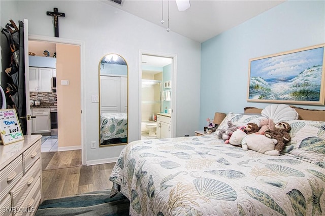 bedroom with ceiling fan, light hardwood / wood-style floors, lofted ceiling, and ensuite bath