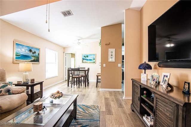 living room featuring ceiling fan, light hardwood / wood-style floors, and lofted ceiling