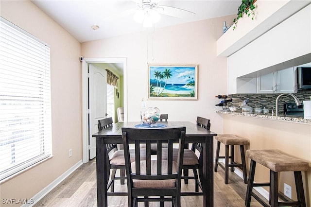 dining area featuring sink, a healthy amount of sunlight, lofted ceiling, and light hardwood / wood-style floors