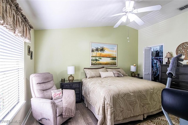 bedroom with ceiling fan, a spacious closet, dark hardwood / wood-style flooring, lofted ceiling, and a closet