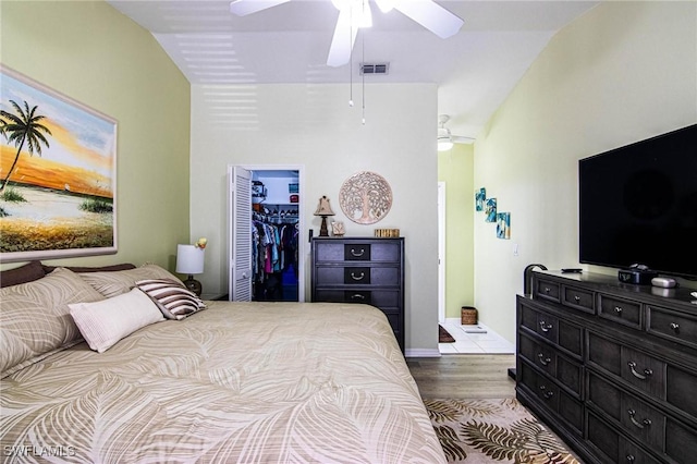 bedroom featuring a walk in closet, vaulted ceiling, light hardwood / wood-style flooring, ceiling fan, and a closet