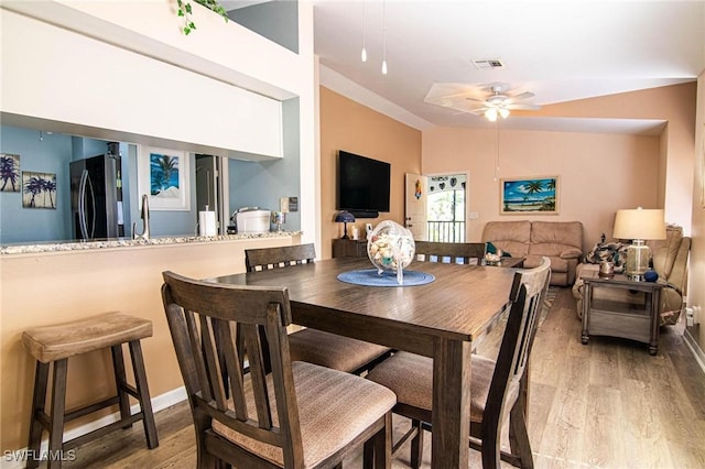 dining area featuring ceiling fan, lofted ceiling, sink, and light hardwood / wood-style flooring