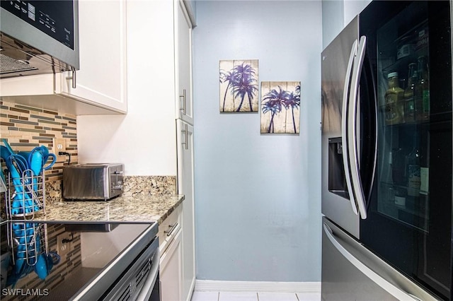 kitchen with light stone countertops, appliances with stainless steel finishes, tasteful backsplash, light tile patterned flooring, and white cabinetry