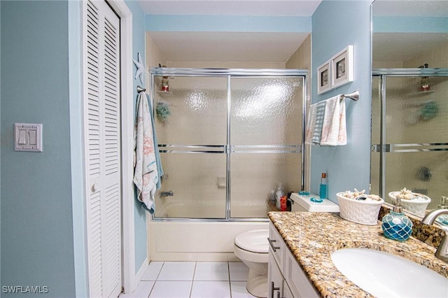 full bathroom with tile patterned flooring, vanity, combined bath / shower with glass door, and toilet