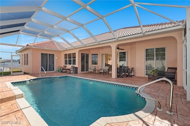 back of house with glass enclosure, ceiling fan, and a patio