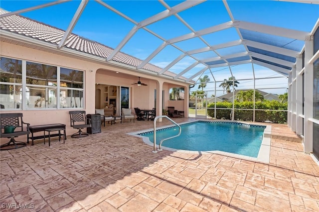 view of swimming pool with glass enclosure, ceiling fan, and a patio area