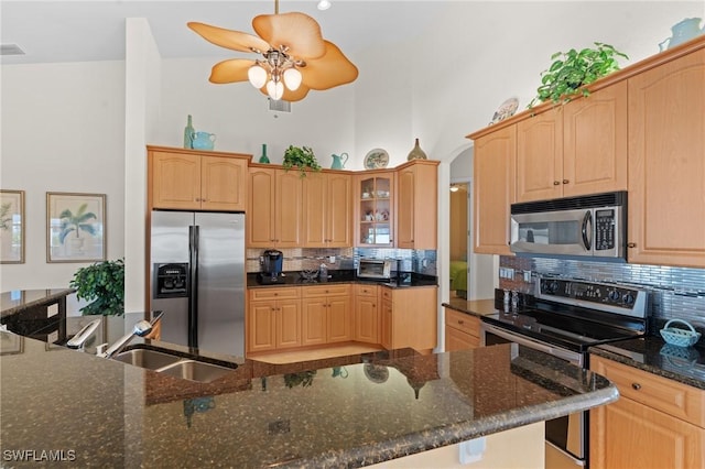 kitchen featuring backsplash, stainless steel appliances, dark stone counters, and sink