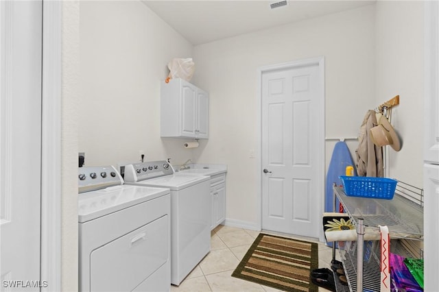 clothes washing area with sink, light tile patterned flooring, cabinets, and independent washer and dryer