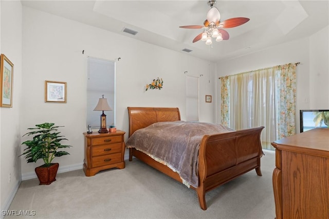 bedroom featuring ceiling fan, light colored carpet, and a tray ceiling