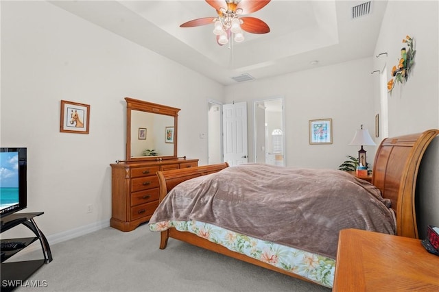 carpeted bedroom with ensuite bath, a raised ceiling, and ceiling fan