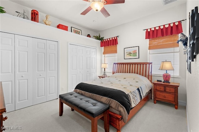 carpeted bedroom featuring ceiling fan and two closets