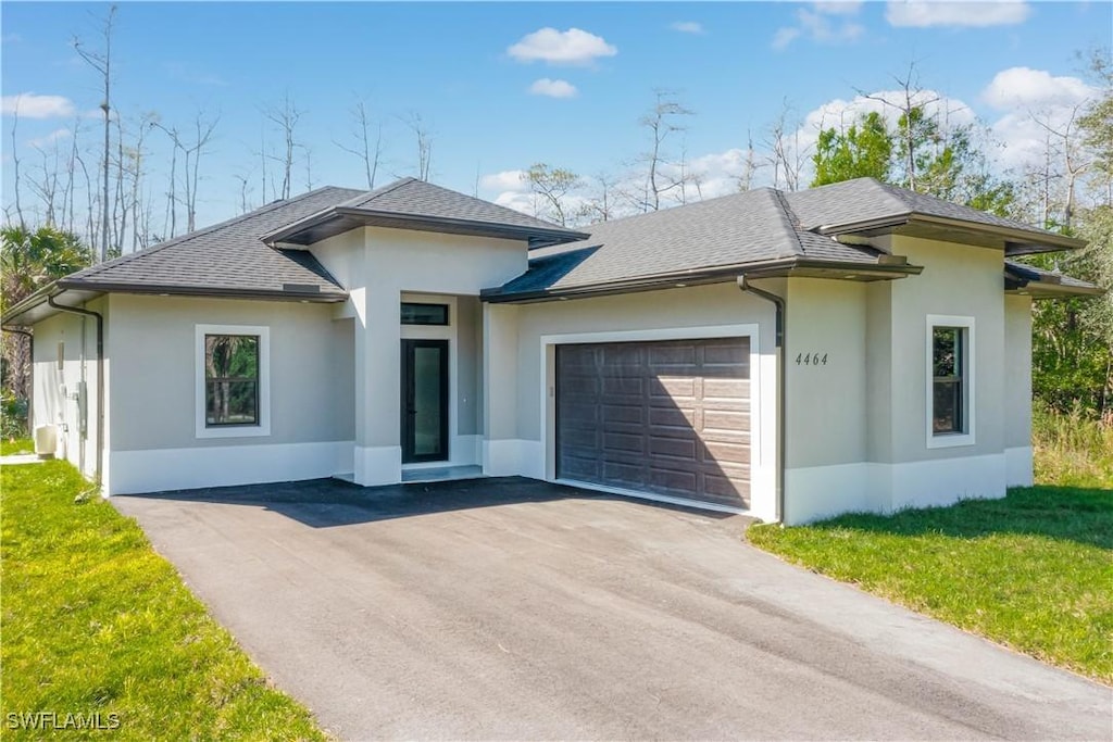 prairie-style home featuring a garage and a front lawn