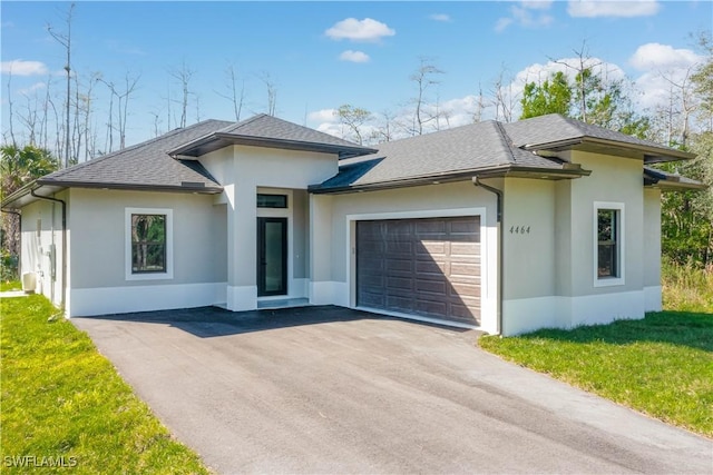 prairie-style home featuring a garage and a front lawn