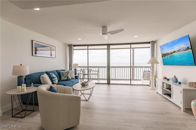 living room with ceiling fan, floor to ceiling windows, and light hardwood / wood-style flooring