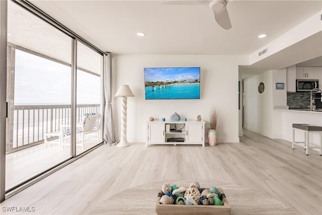 unfurnished living room featuring ceiling fan, light hardwood / wood-style flooring, and a wall of windows