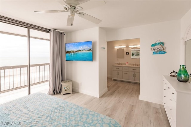 bedroom featuring sink, light hardwood / wood-style flooring, access to exterior, connected bathroom, and expansive windows