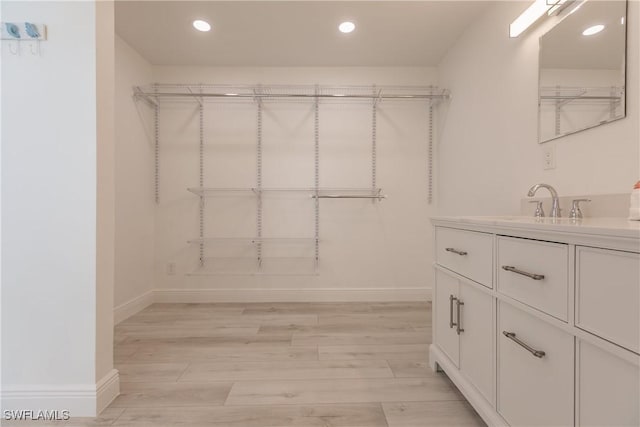 walk in closet with sink and light hardwood / wood-style floors