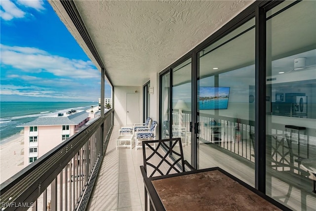 balcony featuring a water view and a view of the beach