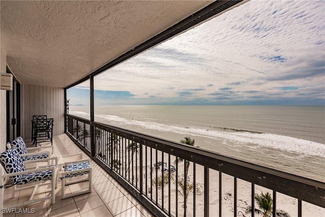 balcony featuring a water view and a view of the beach