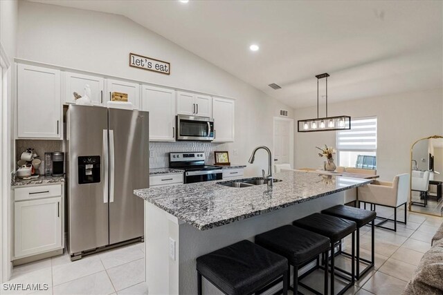 kitchen featuring appliances with stainless steel finishes, a kitchen island with sink, sink, white cabinets, and lofted ceiling