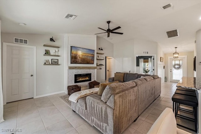 living room with light tile patterned floors, ceiling fan with notable chandelier, and vaulted ceiling