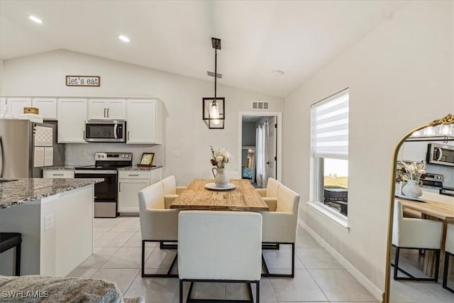 dining space with light tile patterned floors and lofted ceiling