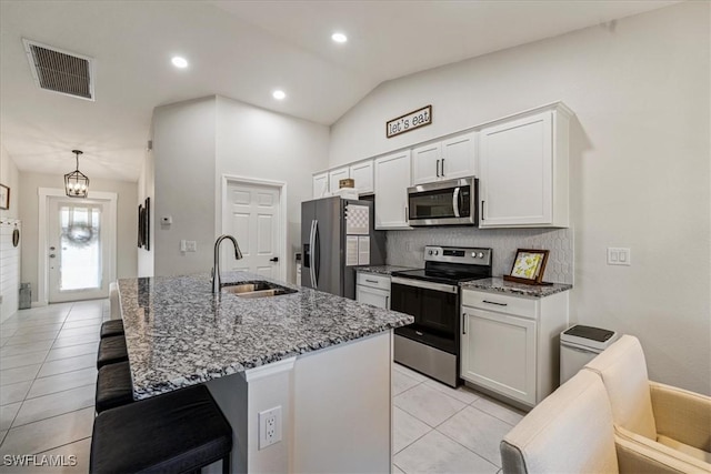 kitchen featuring appliances with stainless steel finishes, vaulted ceiling, white cabinetry, and sink