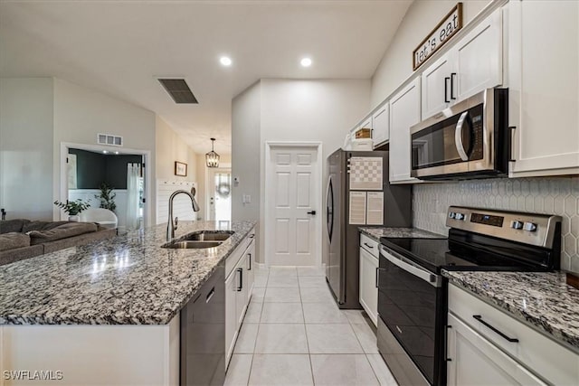 kitchen with lofted ceiling, a kitchen island with sink, sink, white cabinetry, and stainless steel appliances