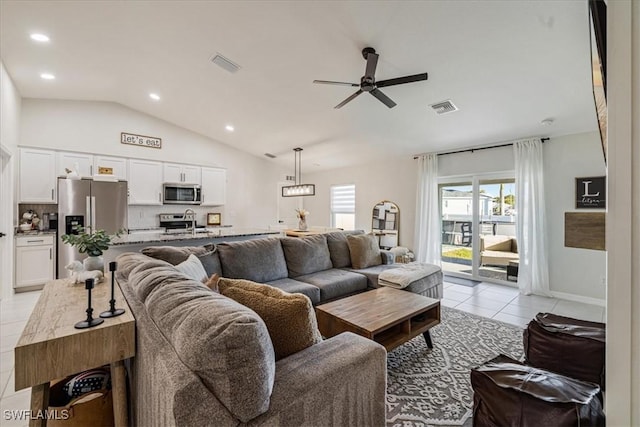 tiled living room with ceiling fan, sink, and vaulted ceiling