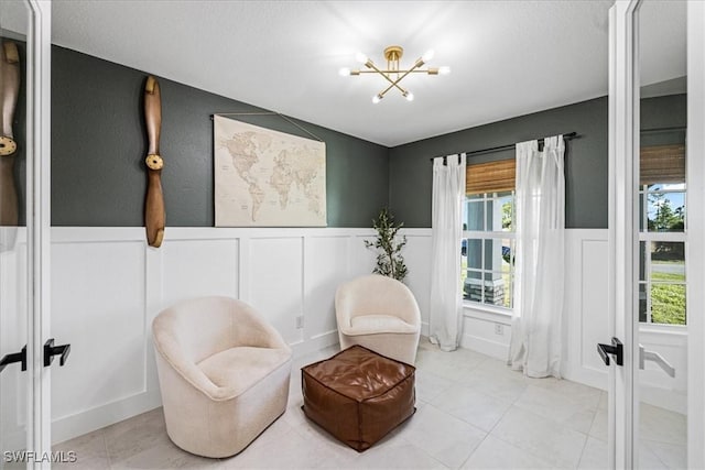 sitting room featuring french doors, light tile patterned floors, and an inviting chandelier