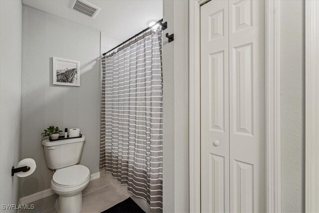 bathroom featuring a shower with curtain, tile patterned flooring, and toilet