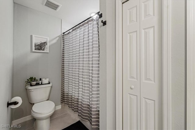 bathroom featuring curtained shower, tile patterned floors, and toilet