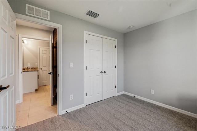 unfurnished bedroom with light colored carpet and a closet