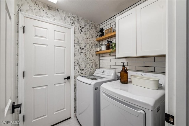 laundry room with cabinets, a textured ceiling, and washing machine and dryer