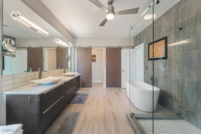 bathroom with shower with separate bathtub, vanity, ceiling fan, and wood-type flooring