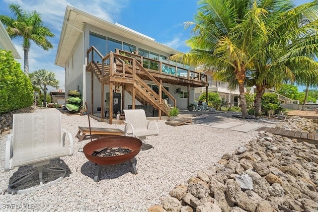 back of house with a wooden deck, a patio area, and an outdoor fire pit