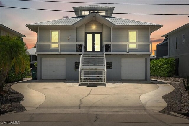 view of front of home featuring covered porch, a garage, and french doors