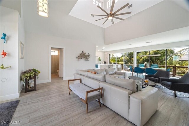 living room with ceiling fan, light hardwood / wood-style floors, and a high ceiling