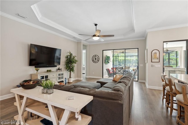 living room featuring a tray ceiling, a wealth of natural light, ceiling fan, and ornamental molding