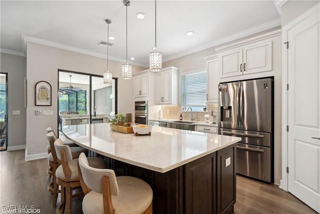 kitchen with white cabinetry, sink, pendant lighting, a kitchen island, and appliances with stainless steel finishes