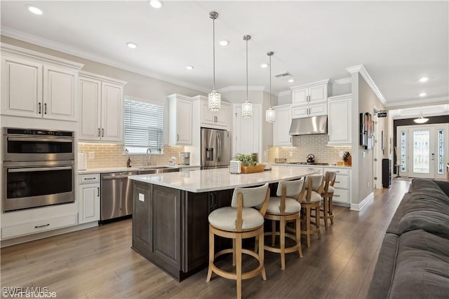 kitchen with white cabinetry, a center island, hanging light fixtures, a breakfast bar area, and appliances with stainless steel finishes