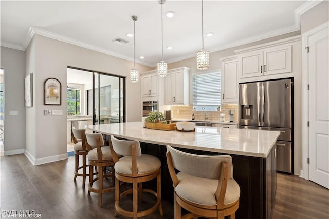 kitchen featuring pendant lighting, dark wood-type flooring, light stone countertops, a kitchen island, and stainless steel appliances