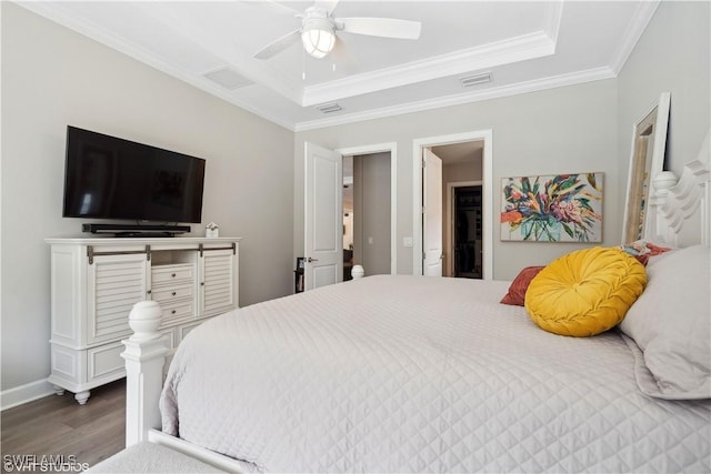 bedroom featuring dark wood-type flooring, ceiling fan, ornamental molding, and a tray ceiling