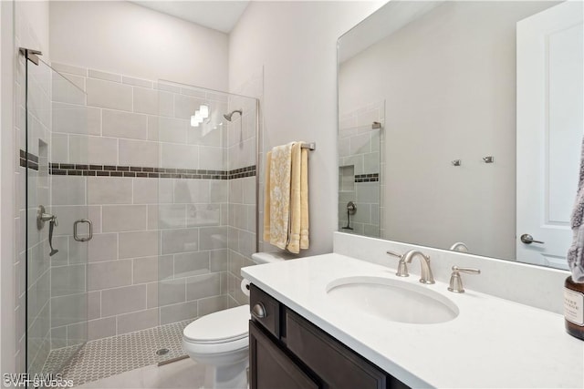 bathroom featuring vanity, a shower with shower door, and toilet