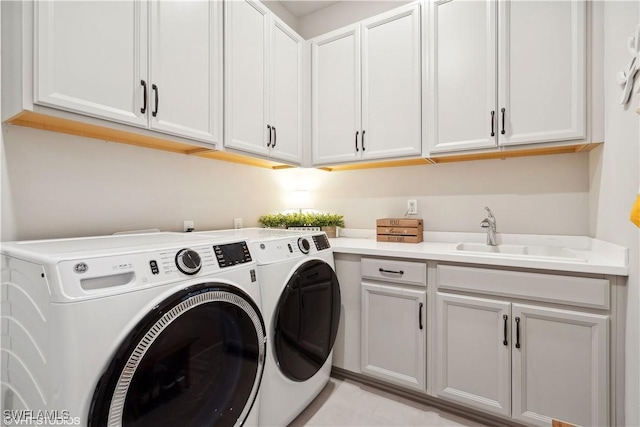 laundry room with cabinets, washing machine and dryer, light tile patterned floors, and sink